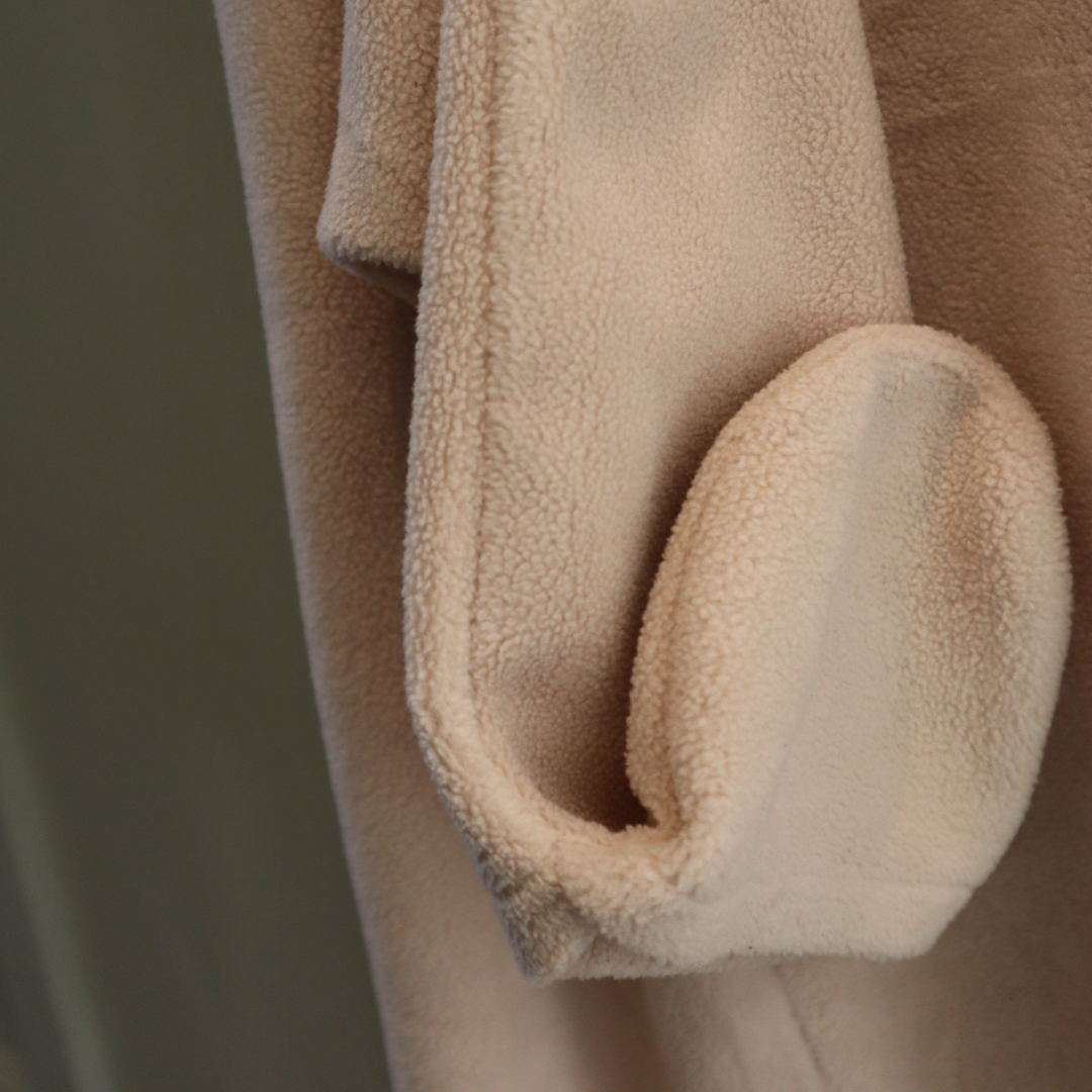 Close-up of a beige fleece blanket with a soft texture.